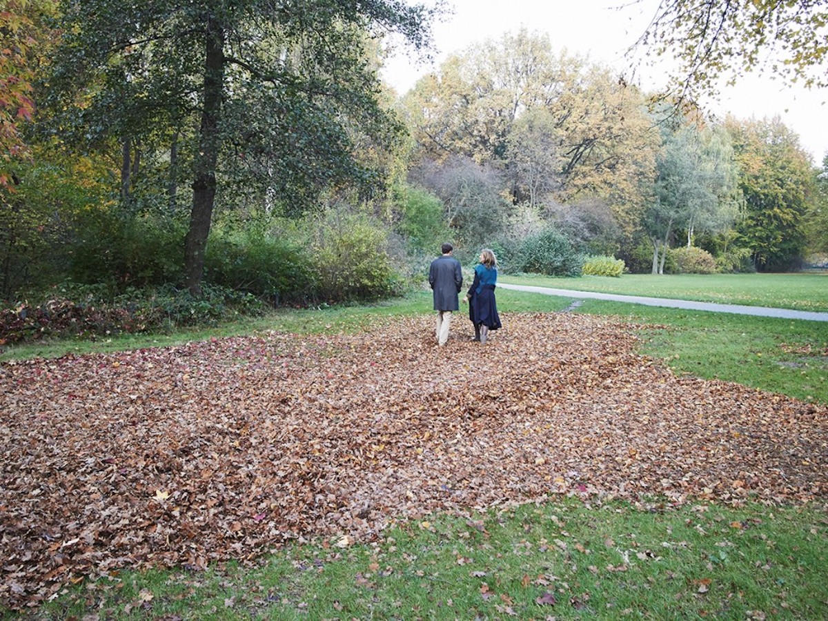 berlin park two people stroll brown leaves